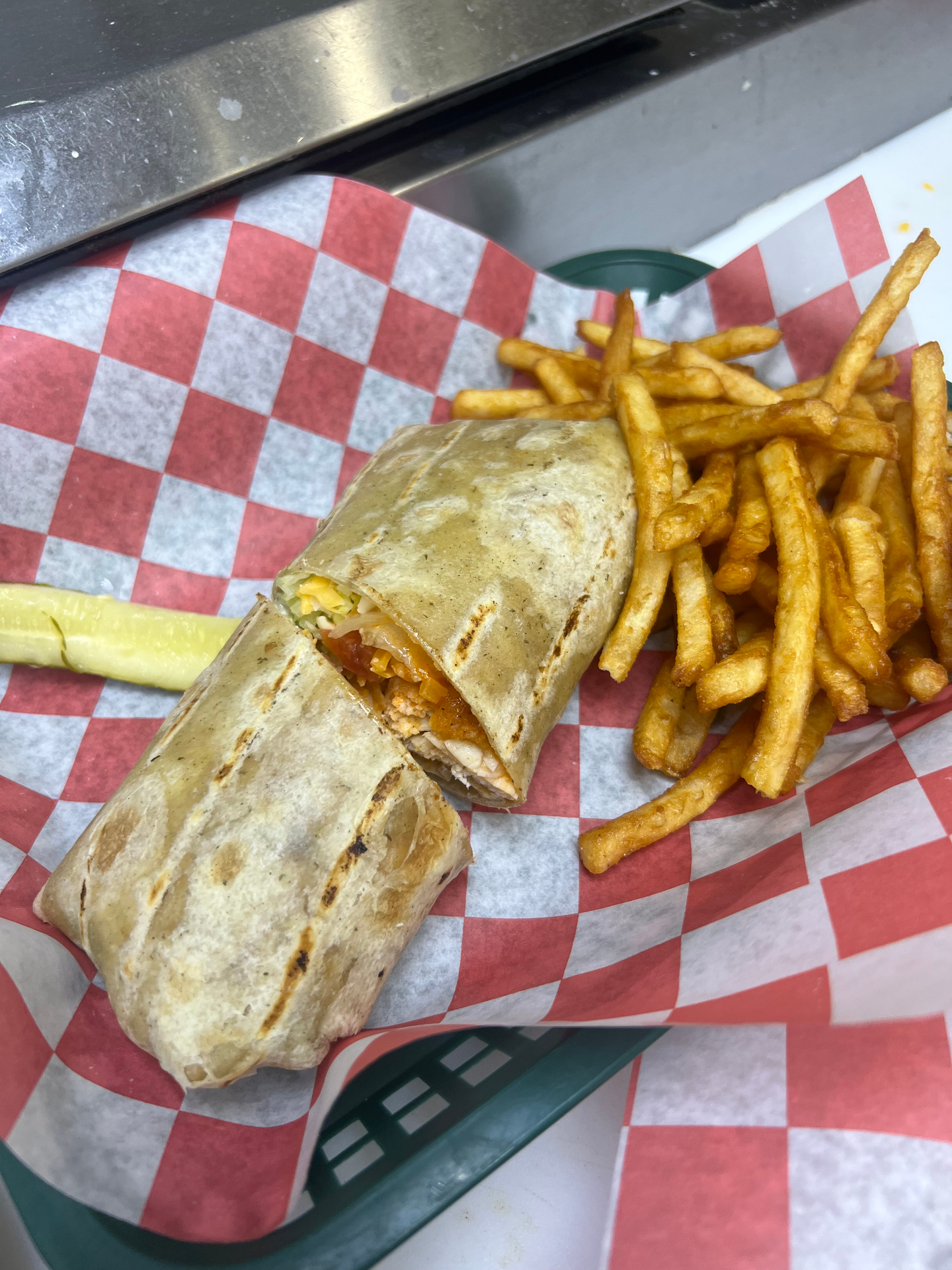 Grilled buffalo chicken wrap with a pickle and fries