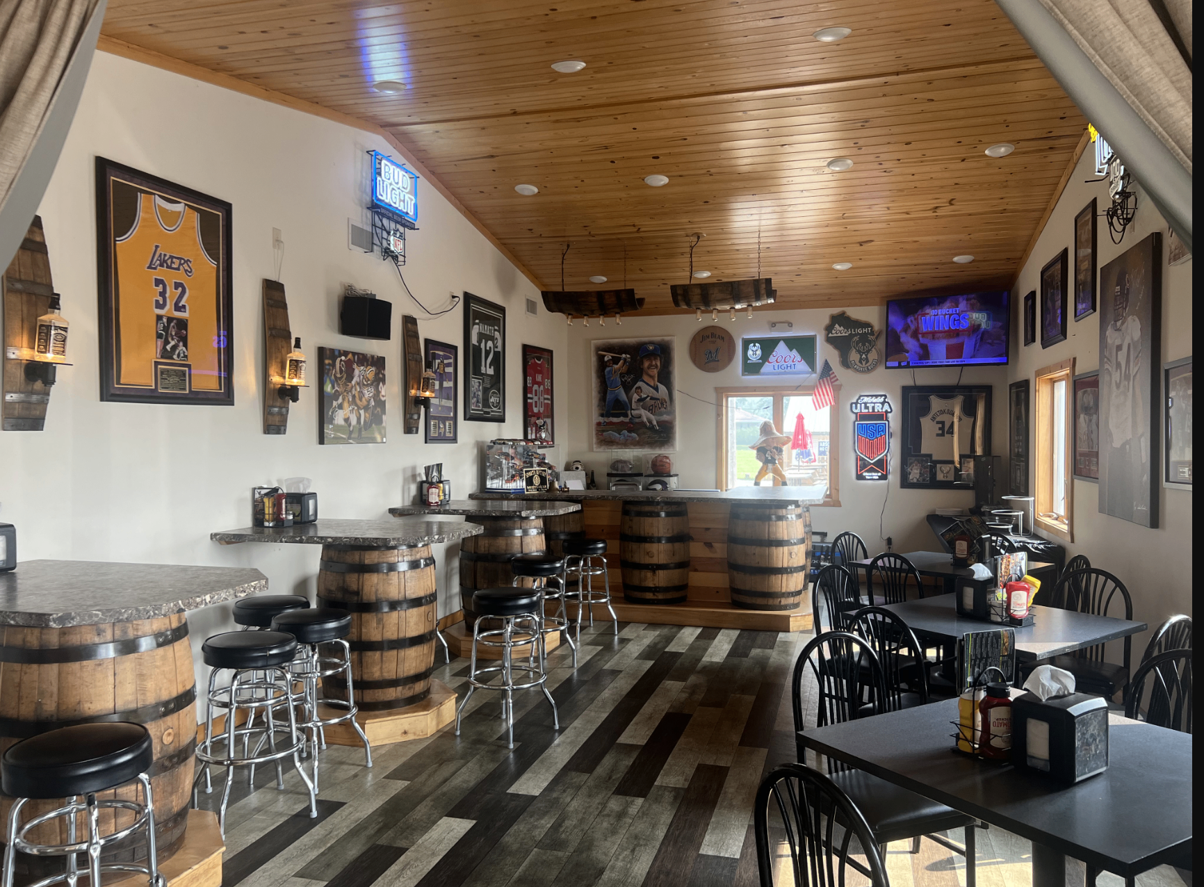 The Backroom at The Zone — barrel tables and stools surrounded by sports memorabilia
