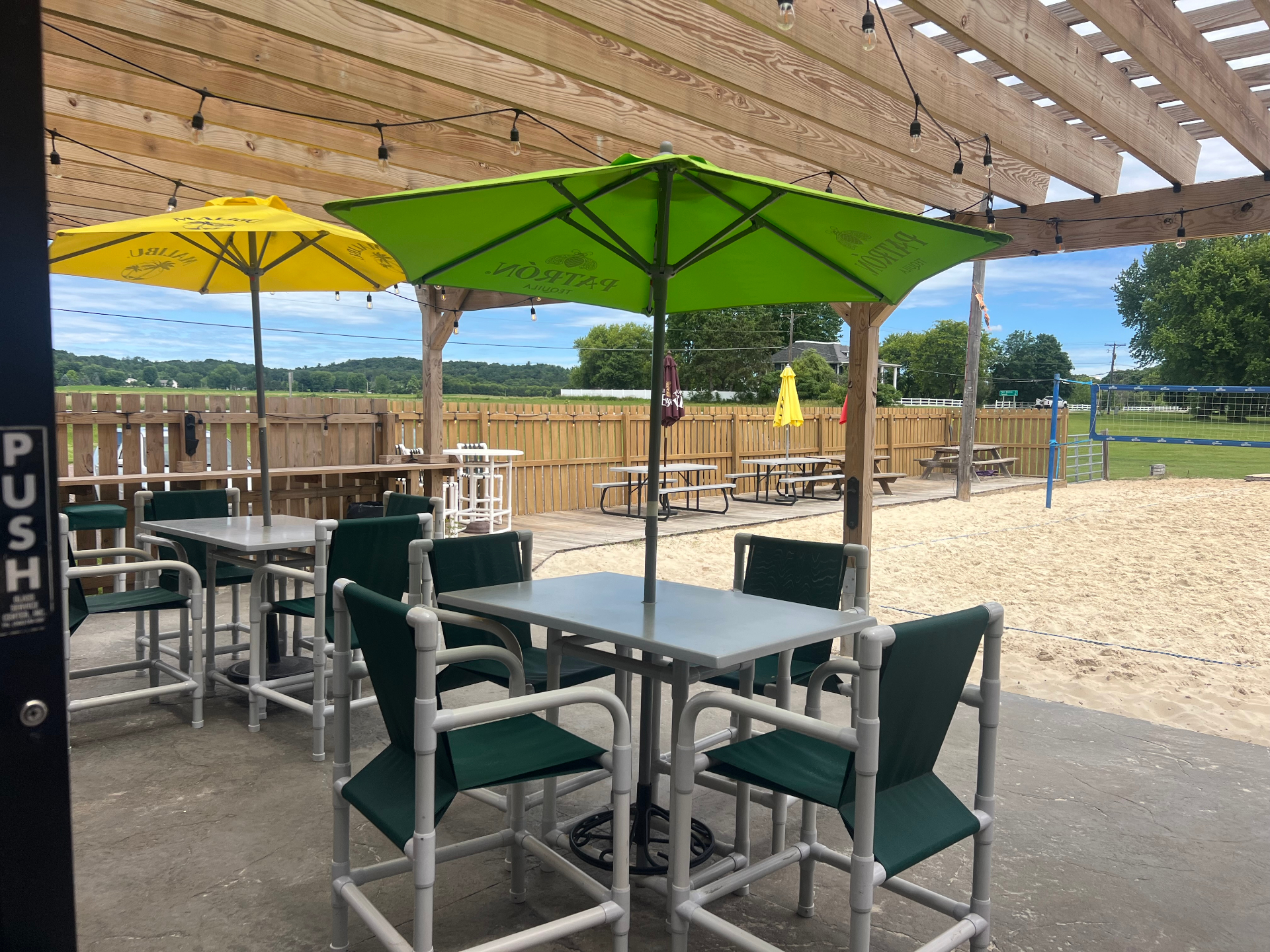 Covered deck seating with view of the sand volleyball court at The Zone